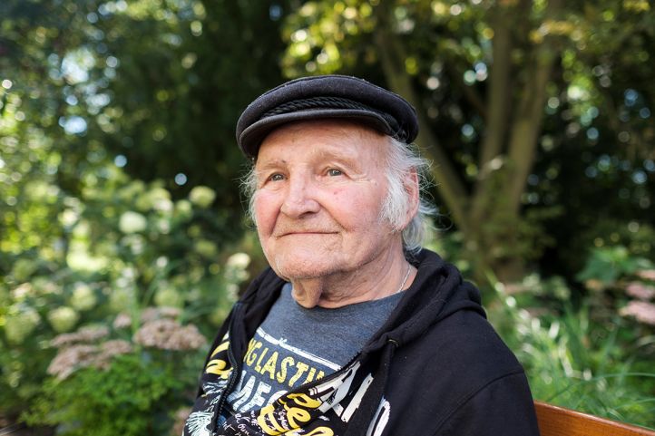 Ein alter Mann Senior sitzt auf einer Parkbank und lächelt