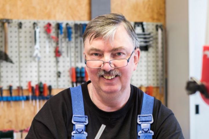 Ein Mann im Blaumann arbeitet in einer Werkstatt an Kabeln in seiner Hand