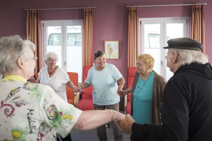 Hier sehen Sie ein Bild, auf dem ältere Menschen im Kreis tanzen