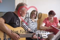 Mann mit Gitarre und zwei Frauen beim Musik machen singen