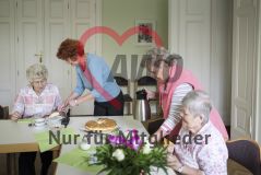 Zwei älteren Damen am Tisch wird von zwei anderen Damen Kuchen gereicht und Kaffee eingeschenkt