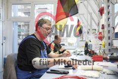 Zwei Männer sitzen an einem mit Deutschlandfahnen dekorierten Schreibtisch und arbeiten mit Kabeln