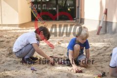 zwei Kinder spielen im Sandkasten mit Autos