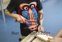 Ein Kind schlägt mit Werkzeug einen Nagel in Holz
