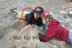 zwei Kinder bauen eine Sandburg