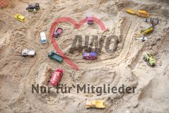 viele Spielzeug Autos liegen im Sand