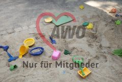 Spielzeuge Eimer Siebe Gießkanne Schaufeln Formen liegen im Sandkasten