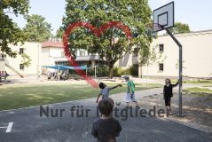 Mehrere Kinder Mädchen und Jungen spielen auf einem Spielplatz an einem Basketballkorb
