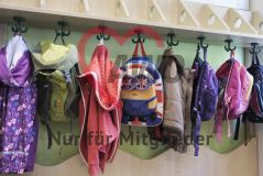 Taschen und Kleidung hängen an einer Garderobe