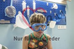 Ein Junge mit Schutzbrille sitzt in einem Labor