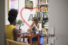 Eine Frau mit Unterlagen spricht mit einer Frau in einem Büro