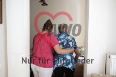 Eine Frau hilft einer alten Frau Seniorin am Bett in einem Pflegeheim