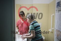 Eine Frau hilft einer alten Frau Seniorin beim Waschen in einem Pflegeheim