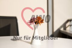 Ein Vase mit Blumen steht auf einem Tisch auf einem sonnigen Balkon