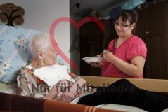 Eine Frau hilft einer alte Frau Seniorin beim Essen in einem Pflegeheim