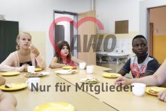 Zwei Mädchen und ein Junge sitzen an einem Tisch und essen