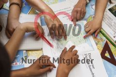 Mehrere Hände zeigen auf eine Deutschlandkarte in einem Heft