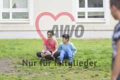 Zwei Jungs sitzen mit einem Fussball im Gras