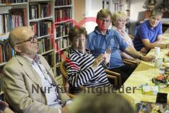 Mehrere alte Männer und Frauen Senioren und Seniorinnen unterhalten sich in einer Gesprächsrunde vor einem Bücherregal