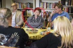 Mehrere alte Männer und Frauen Senioren und Seniorinnen unterhalten sich in einer Gesprächsrunde vor einem Bücherregal