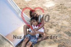 Zwei Kinder Mädchen und Junge auf einem Spielplatz lachen in die Kamera