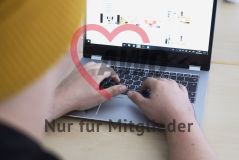 Eine Person mit Mütze arbeitet an einem Laptop Notebook Rechner