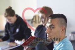Mehrere junge Menschen sitzen in einem Seminar Workshop und ein Mann schaut in einen Ordner