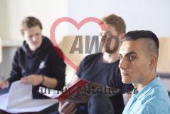 Mehrere junge Menschen sitzen in einem Seminar Workshop und ein Mann schaut in einen Ordner