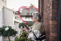Frau kümmert sich auf einem Balkon um Pflanzen