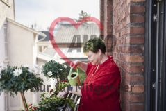 Frau gießt Pflanzen auf einem Balkon 