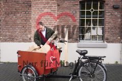 Mann an einem mit Paketen beladenem Lastenrad, am Lenker ein roter AWO-Beutel