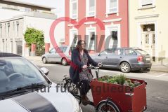 Frau auf mit Pflanzen beladenem Lastenrad auf der Straße