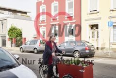 Frau auf mit Pflanzen beladenem Lastenrad auf der Straße