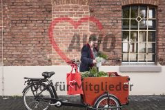 Frau an mit Pflanzen beladenem Lastenrad, roter AWO-Beutel