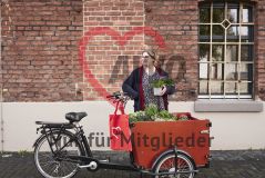 Frau an mit Pflanzen beladenem Lastenrad, roter AWO-Beutel