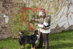 Frau Seniorin an einem Strauch, daneben ein Hund