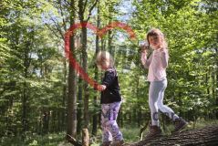 zwei Mädchen im Wald, über einen Baumstamm balancierend
