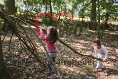 zwei Mädchen im Wald, ein Tipi aus Ästen bauend