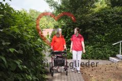 Seniorin mit Rollator und Pflegerin im Garten