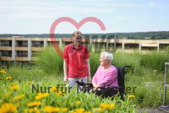 Seniorin im Rollstuhl und Pflegerin im Garten